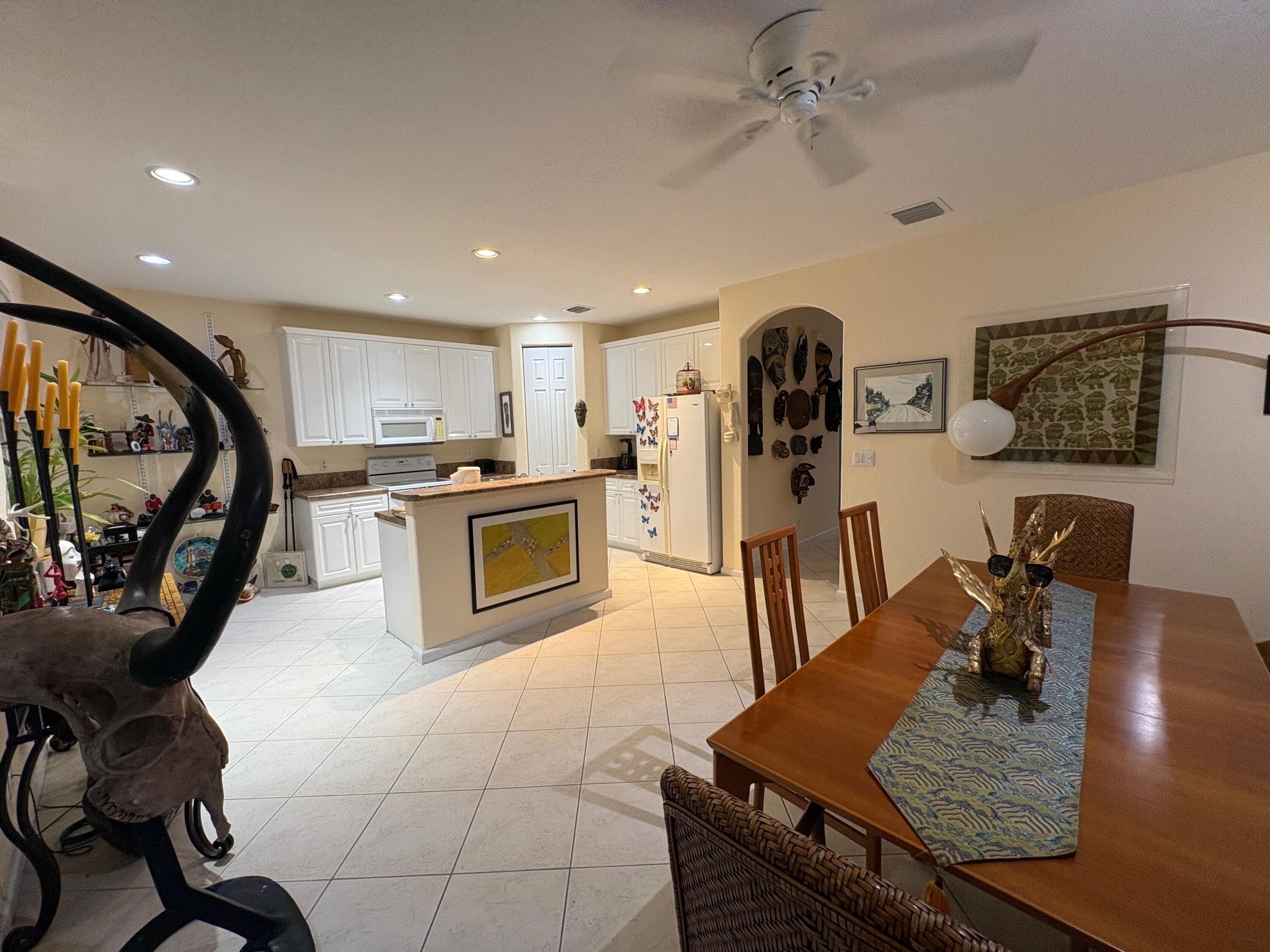 67 Legacy Court Delray Beach, FL 33445 - Photo 5 of 13 a kitchen with stainless steel appliances granite countertop a stove top oven a sink a dining table and chairs with wooden floor