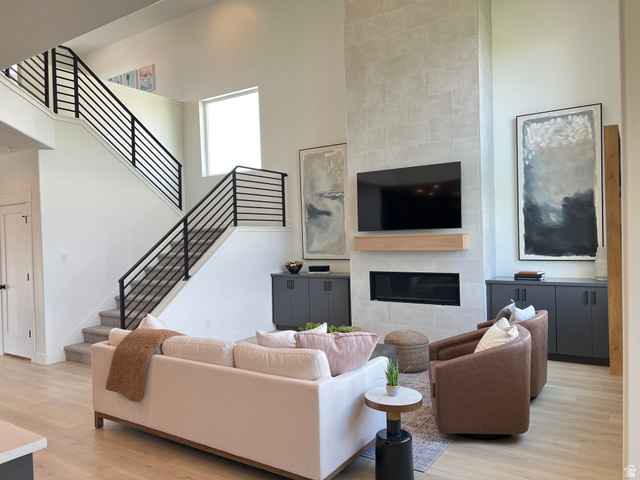 1951 2900 West Provo, UT 84601 - Photo 4 of 21 Great room featuring a two-story ceiling, light wood-finish flooring, and a contemporary fireplace with a light-toned stone surround and wood mantel