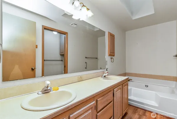 a en suite bathroom with a tub sink and mirror