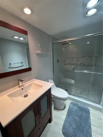 a bathroom with a sink a toilet a mirror and shower
