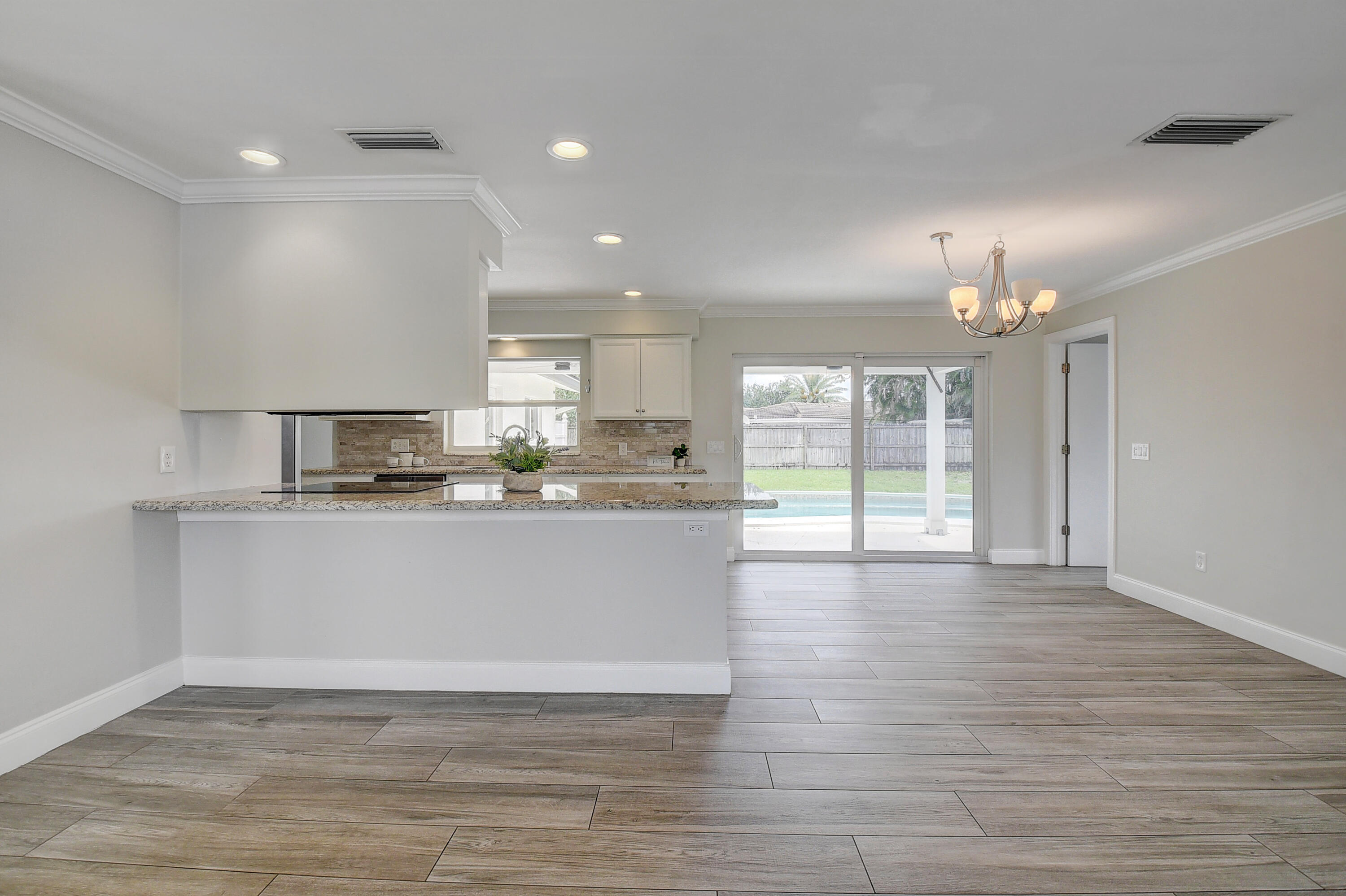 798 Southwest 15th Avenue Boca Raton, FL 33486 - Photo 8 of 27 a big room with wooden floor large windows and kitchen view