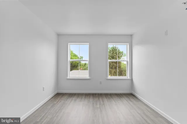 an empty room with wooden floor and window