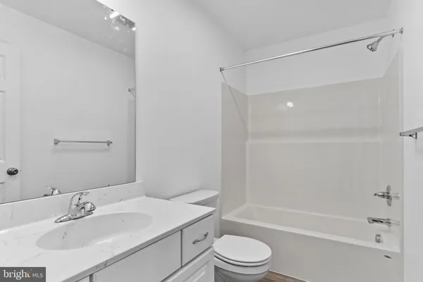 a bathroom with a bathtub shower sink vanity mirror and toilet
