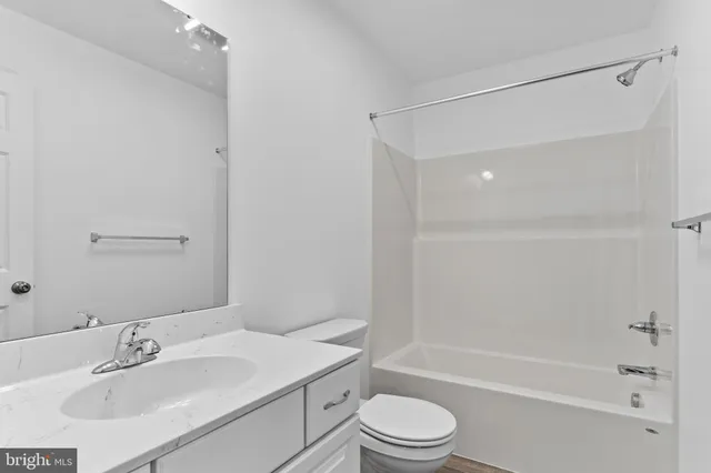 a bathroom with a bathtub shower sink vanity mirror and toilet