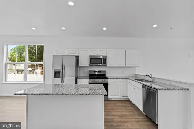a kitchen with stainless steel appliances granite countertop a stove a sink and a refrigerator