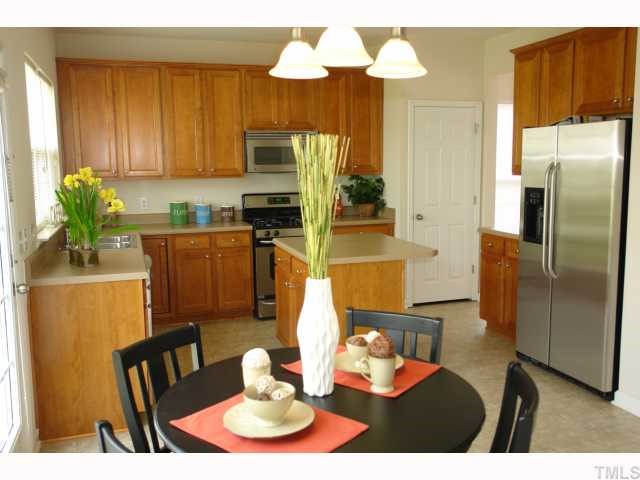 7728 Jackson Dane Drive Raleigh, NC 27613 - Photo 3 of 8 a kitchen with stainless steel appliances granite countertop a refrigerator a microwave a dining table and chairs with wooden floor