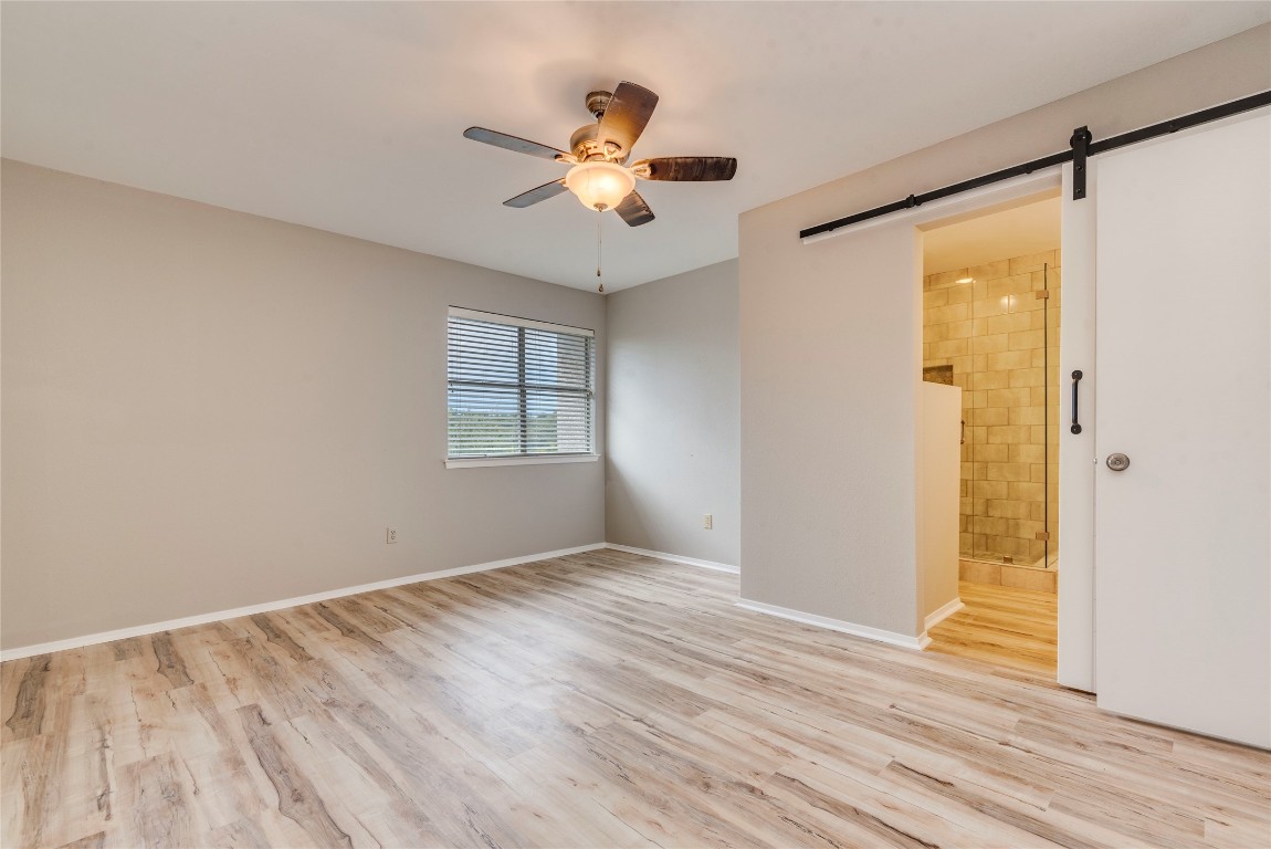 6910 Hart Lane, Unit 805 Austin, TX 78731 - Photo 12 of 17 an empty room with wooden floor chandelier fan and windows