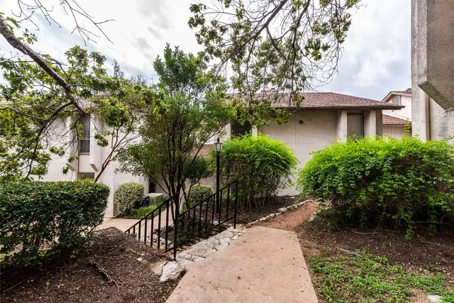 a view of a wooden house with a yard and plants