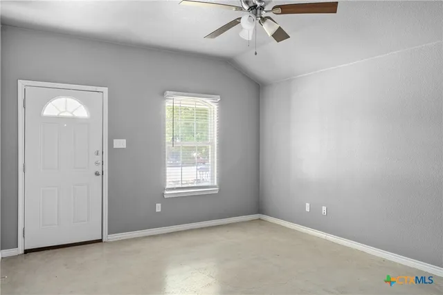 an empty room with windows and fan