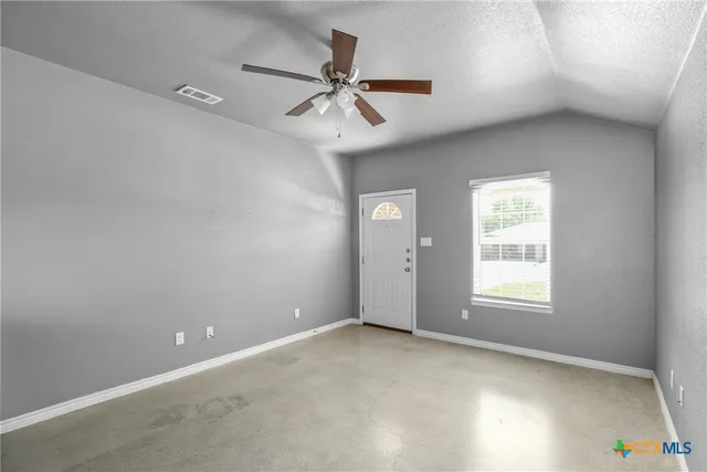 an empty room with windows and fan