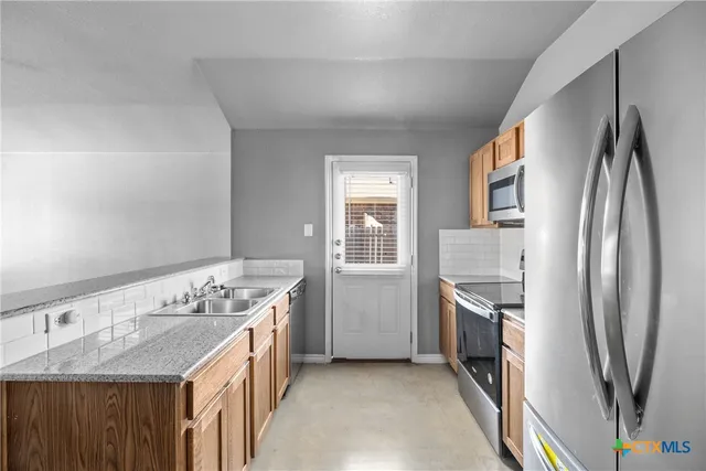 a kitchen with stainless steel appliances granite countertop a sink stove and refrigerator