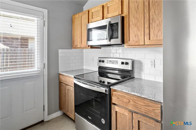 a kitchen with stainless steel appliances granite countertop white cabinets and a stove top oven