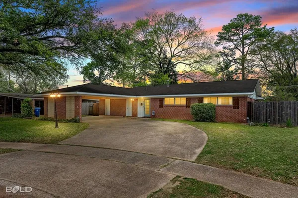 a front view of a house with a yard and trees