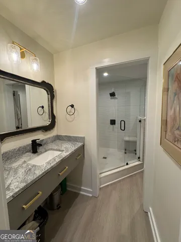 a bathroom with a granite countertop sink a mirror and shower