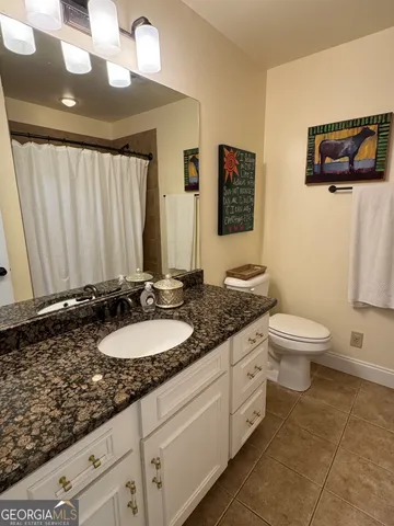 a bathroom with a granite countertop sink a toilet and a mirror
