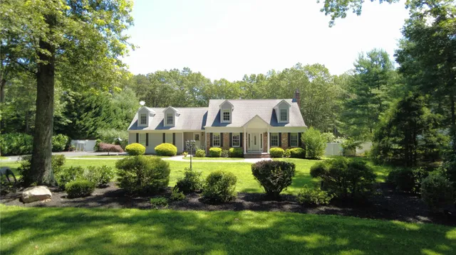 a front view of a house with a garden and trees