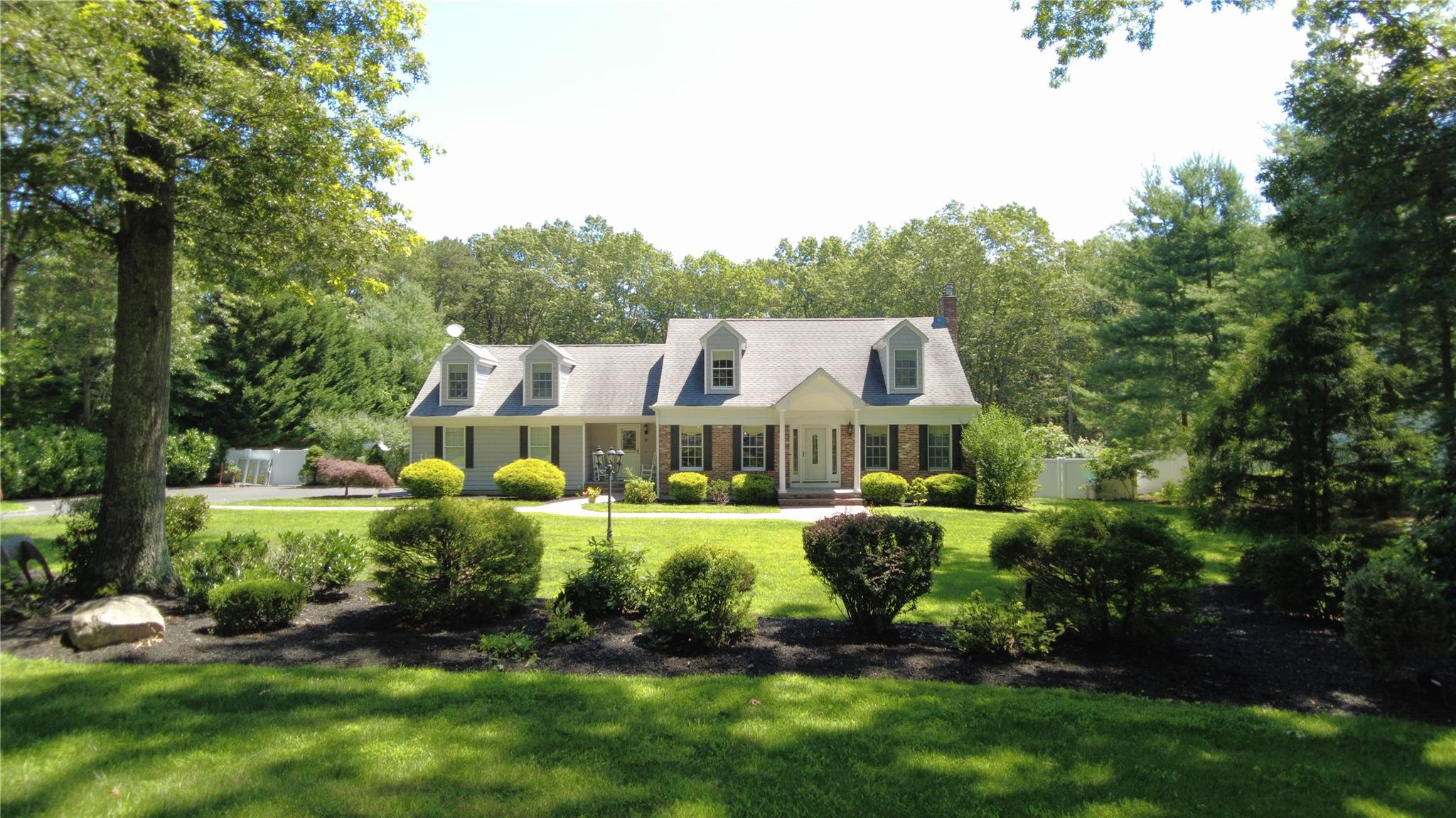 9 Deerfield Drive Wading River, NY 11792 - Photo 1 of 1 a front view of a house with a garden and trees