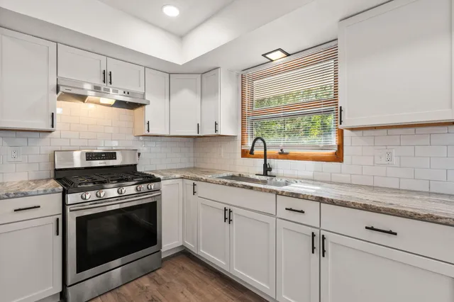 a kitchen with granite countertop a sink cabinets stainless steel appliances and a window