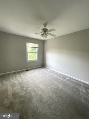 an empty room with windows and chandelier fan