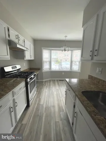 a kitchen with granite countertop stainless steel appliances a sink stove top oven and cabinets