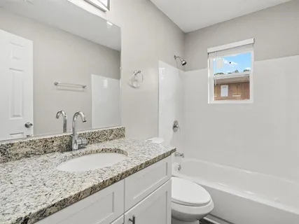 a bathroom with a granite countertop sink a toilet and bathtub