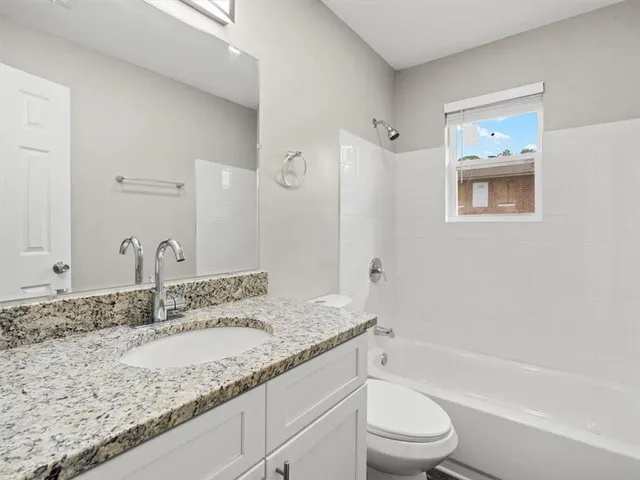 a bathroom with a granite countertop sink a toilet and bathtub