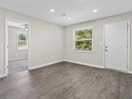 an empty room with wooden floor and windows