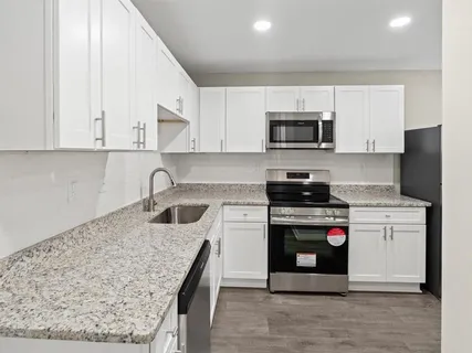 a kitchen with stainless steel appliances granite countertop a stove a sink and a microwave