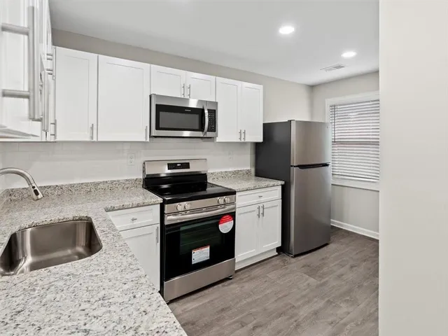 a kitchen with stainless steel appliances granite countertop a stove a sink dishwasher a refrigerator and a microwave