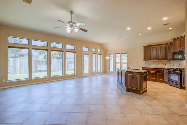 a large kitchen with granite countertop a stove a sink a counter space and cabinets