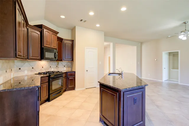 a kitchen with stainless steel appliances granite countertop a stove a sink and a microwave