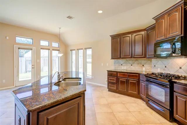 a kitchen with stainless steel appliances granite countertop a stove a sink and a microwave