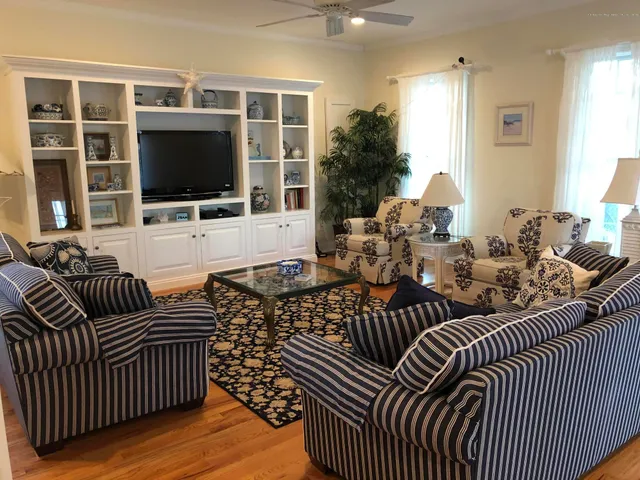 a living room with furniture a flat screen tv and a floor to ceiling window