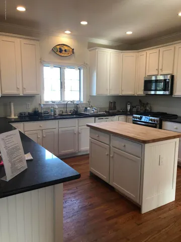 a kitchen with granite countertop a sink cabinets and wooden floor