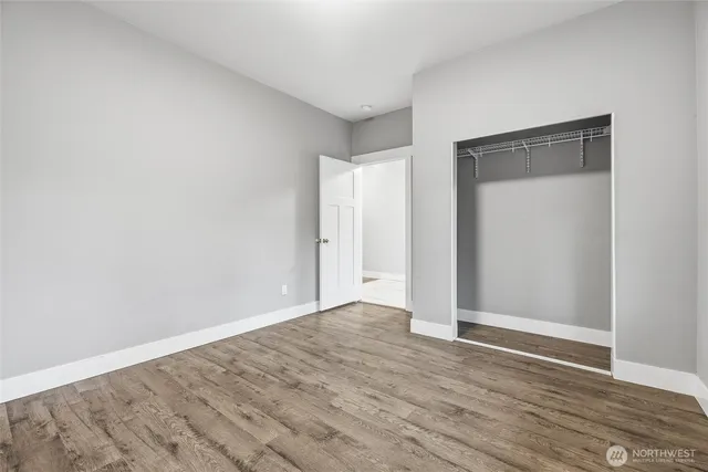 a view of an empty room with wooden floor and closet