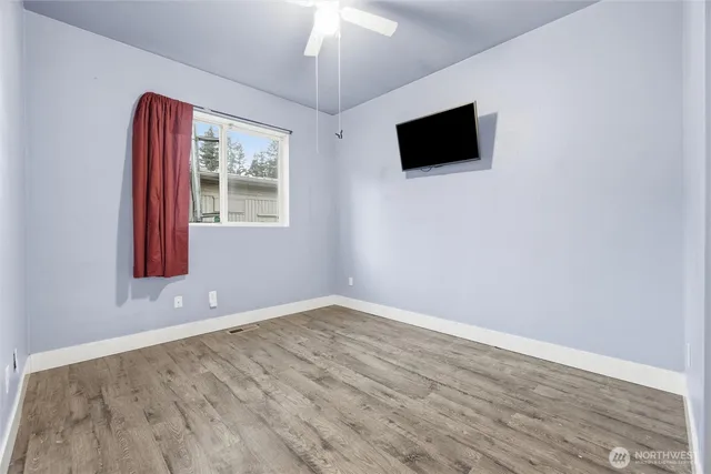 an empty room with wooden floor and windows