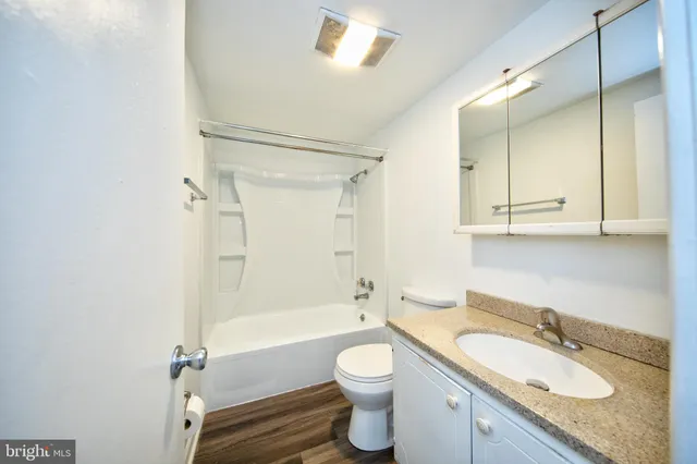 a bathroom with a granite countertop toilet sink and mirror