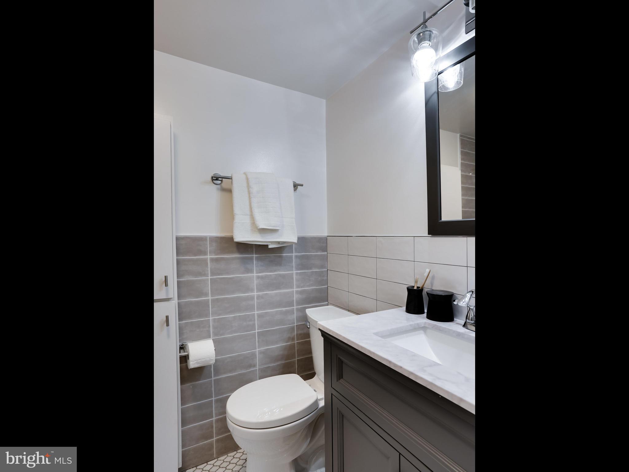 4201 Cathedral Avenue Northwest, Unit 703W Washington, DC 20016 - Photo 15 of 20 a bathroom with a granite countertop toilet sink and mirror