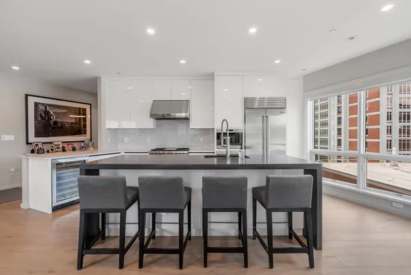 a kitchen with stainless steel appliances granite countertop a stove a sink a microwave a island and chairs in it