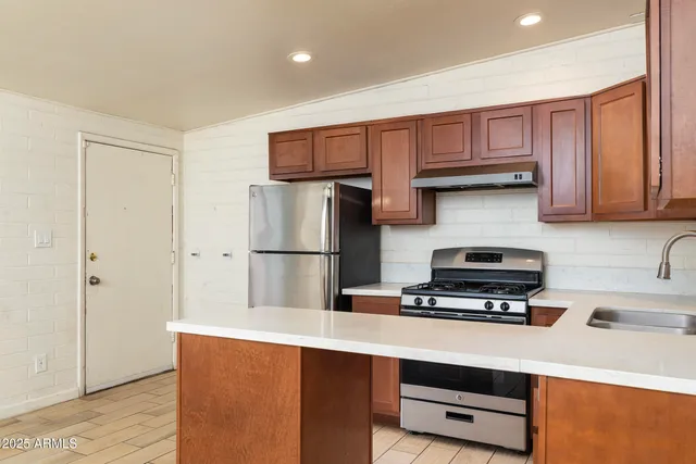 a kitchen with stainless steel appliances a refrigerator a sink and cabinets