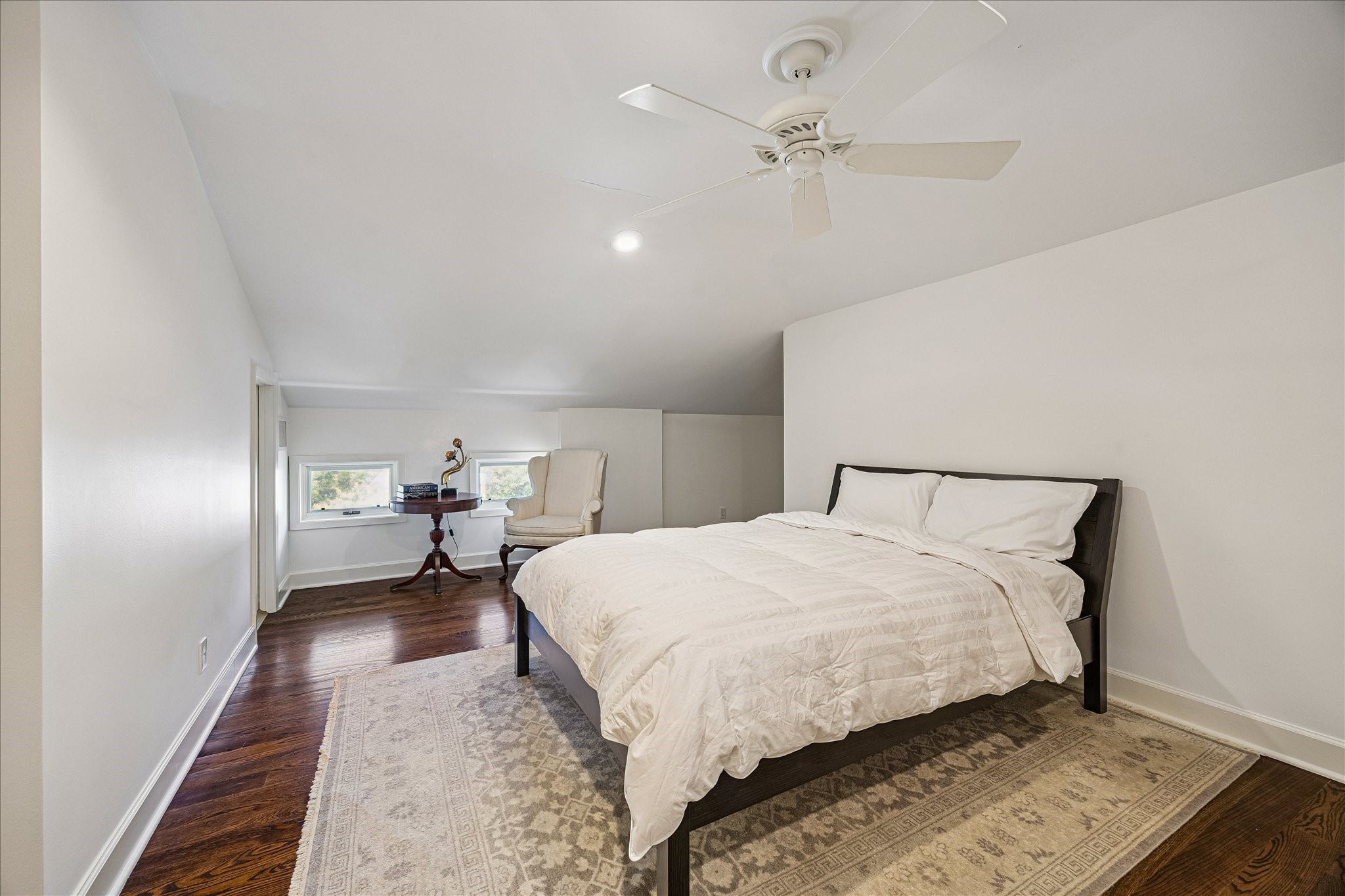 2368 Timber Lane Houston, TX 77027 - Photo 39 of 46 Located on the third level, this spacious bedroom retreat perfect for a live-in nanny or as a mother-in-law suite. It features rich hardwood floors, a soaring pitched ceiling, and an overhead fan with remote control for added comfort. A thoughtfully designed dividing wall creates dual access to a private study nook, offering flexibility for work, reading, or quiet relaxation.