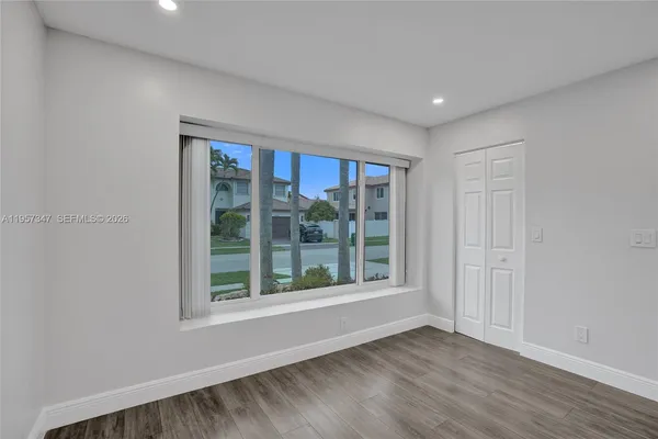 a view of an empty room with wooden floor and a window