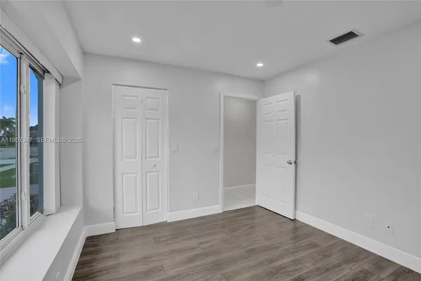 an empty room with chandelier fan and wooden floor