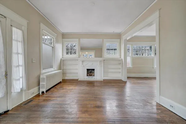 a view of a livingroom with wooden floor and a fireplace