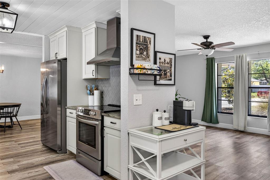 9043 Mc Cormick Street Spring Hill, FL 34608 - Photo 12 of 47 a kitchen with stainless steel appliances a stove a refrigerator and a dining table with wooden floor