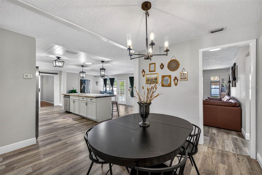 9043 Mc Cormick Street Spring Hill, FL 34608 - Photo 27 of 47 a view of a dining room and livingroom with furniture wooden floor a chandelier