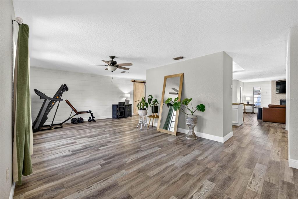 9043 Mc Cormick Street Spring Hill, FL 34608 - Photo 8 of 47 a view of a livingroom with wooden floor and a ceiling fan