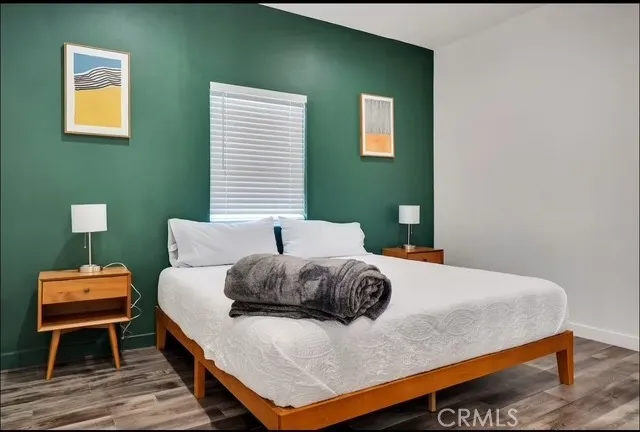 a bedroom with a bed a flat screen tv and windows