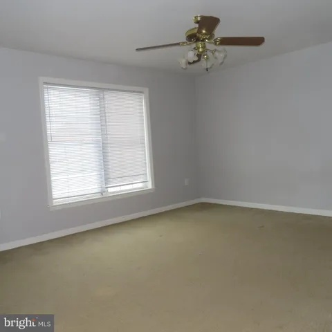 an empty room with a chandelier fan and windows