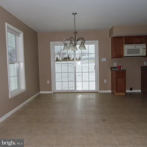 a view of a livingroom with chandelier and kitchen space